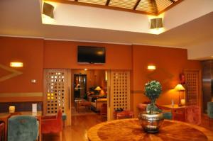 uma sala de estar com uma mesa e uma televisão na parede em Hotel Central Parque em Maia