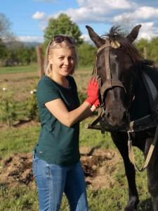 a woman is standing next to a horse at Tiny House - Baia de Fier in Baia de Fier