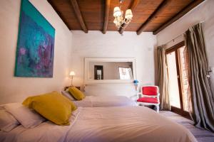 1 dormitorio con 2 camas y silla roja en Pueblo Indio en Tilcara