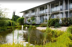 ein Gebäude mit einem Teich vor einem Gebäude in der Unterkunft Hotel am Waldbad in Uelsen