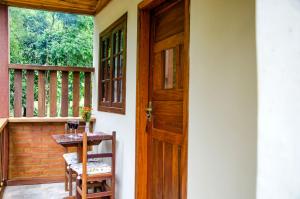 Chalés Luz da Montanha في Núcleo Mauá: باب إلى شرفة مع طاولة ونافذة