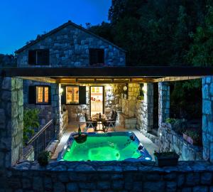 una piscina nel cortile di una casa in pietra di notte di Stonehouse Korlat with open-air jacuzzi a Podšpilje