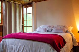 a bedroom with a large bed with a purple blanket at Chalés Luz da Montanha in Núcleo Mauá