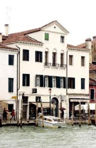 un gran edificio blanco con un barco en el agua en Hotel Airone, en Venecia