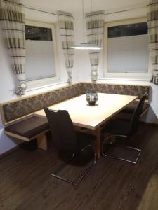 a table and chairs in a room with two windows at Gästehaus Holaus in Mayrhofen