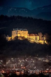 un gran castillo en la cima de una colina por la noche en Mníchov dvor, en Slovenská ľupča