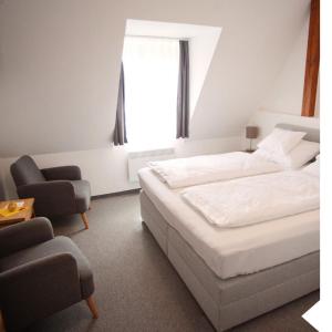 a bedroom with a bed and a chair and a window at Haus56 in Podersdorf am See