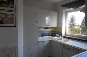 eine weiße Küche mit einem Waschbecken und einem Fenster in der Unterkunft Komfortferienwohnung in ruhiger Lage mit 128qm in Grömitz in Grömitz