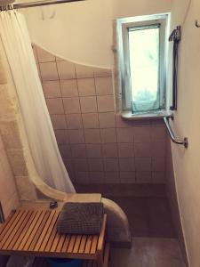 La salle de bains est pourvue d'une douche avec un banc et une fenêtre. dans l'établissement Mater Bed & Food-Riserva Naturale di Torre Guaceto, à Serranova