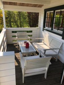 a porch with white chairs and a table and benches at Sfeervolle Blokhut in Oostvoorne