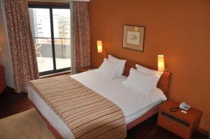 a bedroom with a large bed and a window at Hotel Central Parque in Maia