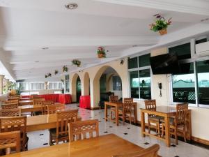 ヤンゴンにあるグランド ローレル ホテルの木製のテーブルと椅子、薄型テレビが備わるレストランを提供しています。