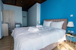 a bedroom with a large white bed with a blue wall at Poseidon Apartments in Tolo