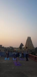 a group of people doing yoga in a park at Padma Guest House in Hampi