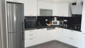 a kitchen with white cabinets and a stainless steel refrigerator at Versi in Tučepi
