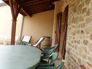 - une table et des chaises dans une pièce dotée d'un mur en pierre dans l'établissement La maison du vigneron, à Ternand