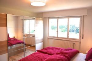 a bedroom with a bed and a large window at Plage & Montagne - Appartement familial à proximité de la plage de Préverenges in Preverenges