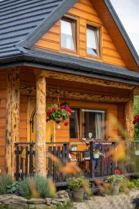 una casa de madera con un porche con flores. en Chaty Anety Domki Całoroczne en Solina