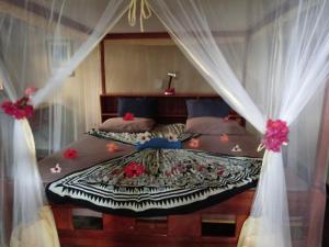 a bedroom with a bed with curtains and flowers on it at Finca Montania Sagrada in Mérida