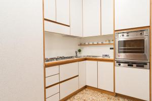 een keuken met witte kasten en een roestvrijstalen oven bij Rialto Dream - Wifi in Venetië