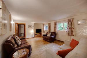 ein Wohnzimmer mit einem Sofa, Stühlen und einem TV in der Unterkunft Landews Meadow Cottages in Badlesmere
