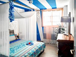 Aloha Home في لوس أبريغوس: غرفة نوم بسرير مظلة عليها بقع زرقاء وبيضاء