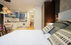 a bedroom with a white bed and a kitchen at DE LA GUARDIA LOFT ROSAL in Oviedo