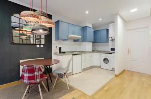 a kitchen with blue cabinets and a table and chairs at DE LA GUARDIA LOFT ROSAL in Oviedo