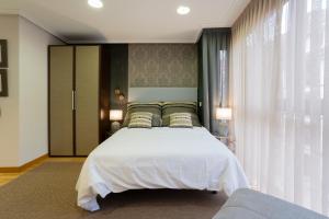 a bedroom with a large white bed and a window at DE LA GUARDIA LOFT ROSAL in Oviedo +13 photos