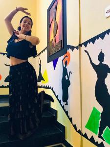 a woman standing on stairs in front of a wall with a mural at Indian Art Villa in Varkala