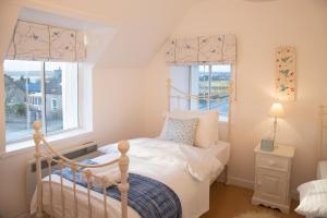 a small bedroom with a bed and two windows at The Corner Cottage in Sandwick
