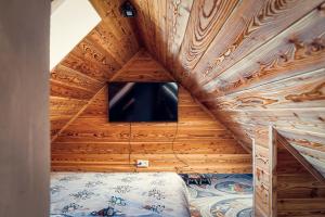 a bedroom with a tv in a wooden ceiling at Bury Miś in Jaworki