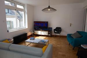 Una sala de estar con un sofá, una mesa y un televisor. en Les Aigrettes - Appartement spacieux - Terrasse et garage, en Concarneau