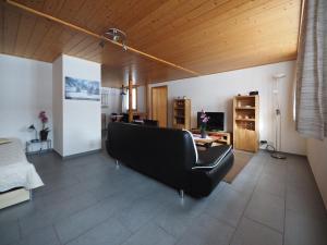ein Wohnzimmer mit einem schwarzen Sofa und einem Tisch in der Unterkunft Holidayapartment Sydach in Wilderswil