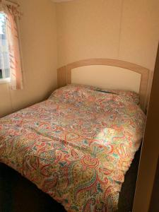 a bed with a colorful blanket on it in a bedroom at Boquhanran Caravan, Whitley Bay in Hartley