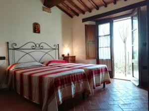 a bedroom with a bed with a red and white blanket at Agriturismo Ombianco in Seggiano
