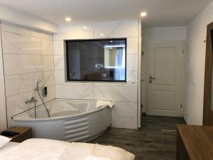 ein weißes Badezimmer mit Badewanne und Fenster in der Unterkunft ASADOR Hotel & Restaurant GmbH in Netphen