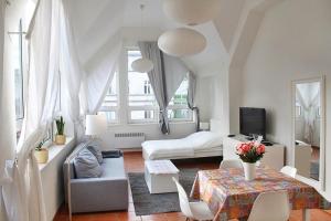 a white living room with a bed and a table at Apartament Central Sopot in Sopot