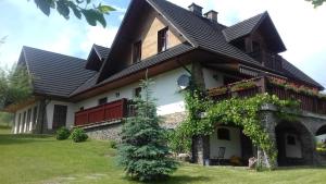 a house with a black roof and a green yard at Apartamenty Ancymon in Węgierska Górka