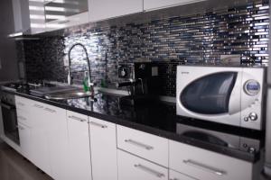 a kitchen with a microwave and a sink at Apartament Denissia in Oradea