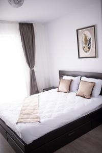 a bedroom with a bed with white sheets and a window at Apartament Denissia in Oradea