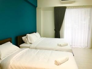 two beds in a room with blue walls and a window at By The Beach - Luxury 2 Bedrooms Family Suite in Batu Ferringhi