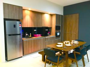 uma cozinha com uma mesa de madeira e um frigorífico em By The Beach - Luxury 2 Bedrooms Family Suite em Batu Ferringhi