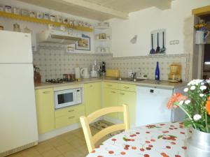 a kitchen with yellow cabinets and a white refrigerator at LA MAISON BLEUE in Saint-Gelais