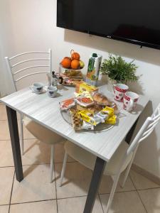 einen weißen Tisch mit einem Teller Essen drauf. in der Unterkunft La casetta 75 in Neapel