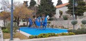 een blauwe speeltuin in een park naast een gebouw bij Apartments Zafranović in Prvić Luka