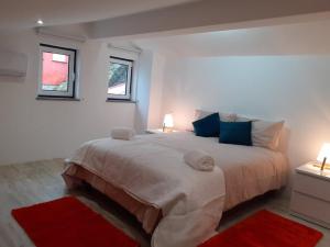 a white bedroom with a large bed with two windows at Casa das Relvas in Penalva de Alva