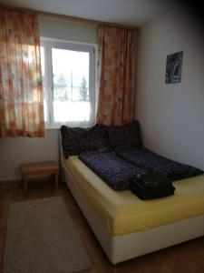 Dormitorio pequeño con cama y ventana en Ferienwohnung mit Blick auf die Buchensteinwand, en Hochfilzen