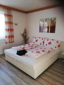 ein Schlafzimmer mit einem weißen Bett mit roten Blumen darauf in der Unterkunft Ferienwohnung mit Blick auf die Buchensteinwand in Hochfilzen