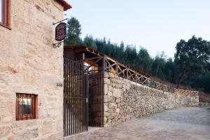 a stone wall next to a building with a gate at Casa do Avô in Cinfães